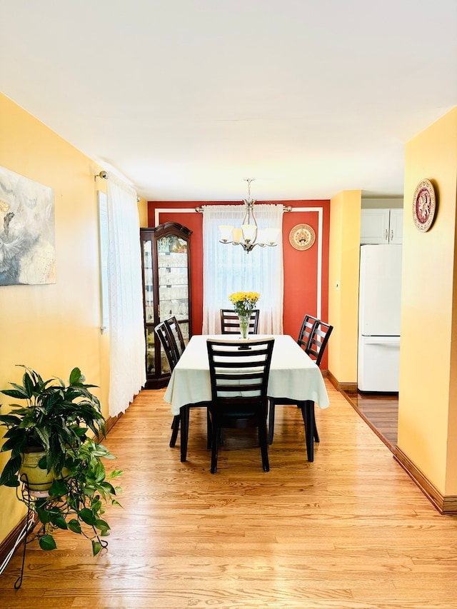 dining room with light hardwood / wood-style flooring and a notable chandelier