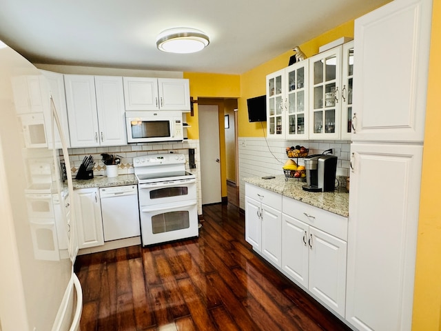 kitchen with light stone counters, white cabinetry, backsplash, dark wood-type flooring, and white appliances