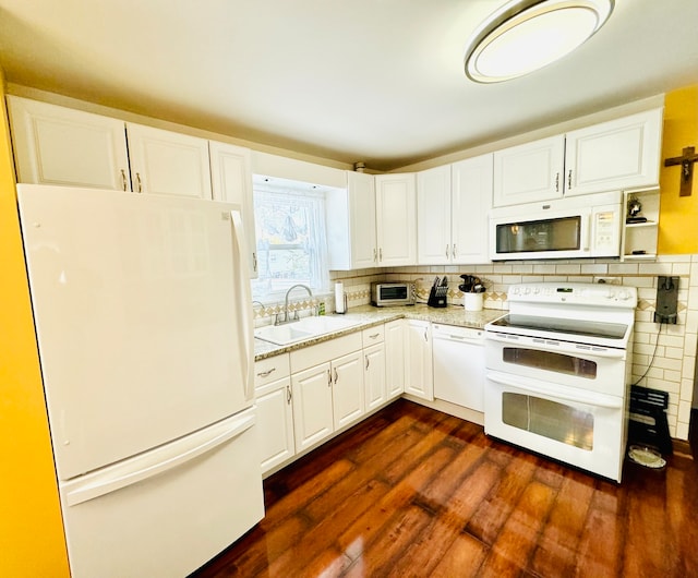 kitchen with light stone counters, white cabinets, sink, dark hardwood / wood-style floors, and white appliances