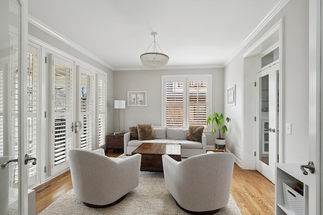 living room featuring crown molding, french doors, and light wood-type flooring