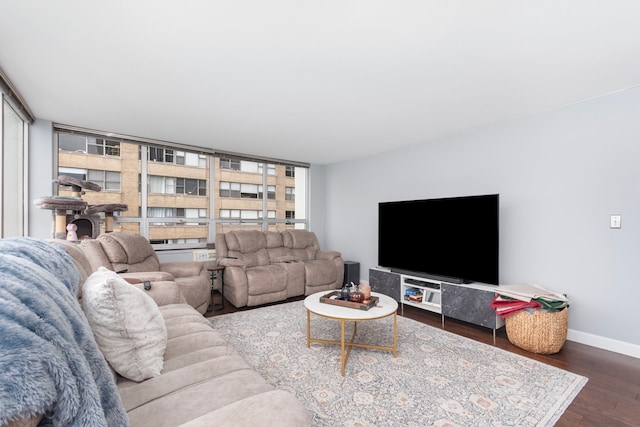 living room with dark hardwood / wood-style floors, a wall of windows, and a healthy amount of sunlight