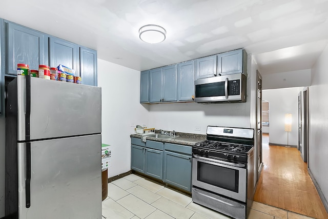 kitchen featuring light wood-type flooring, stainless steel appliances, blue cabinets, and sink