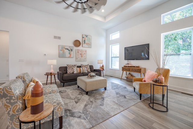 living room featuring light hardwood / wood-style floors, a healthy amount of sunlight, and a towering ceiling