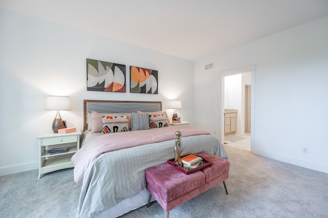 bedroom with light colored carpet and ensuite bath