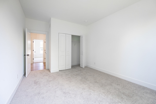 unfurnished bedroom featuring light carpet and a closet