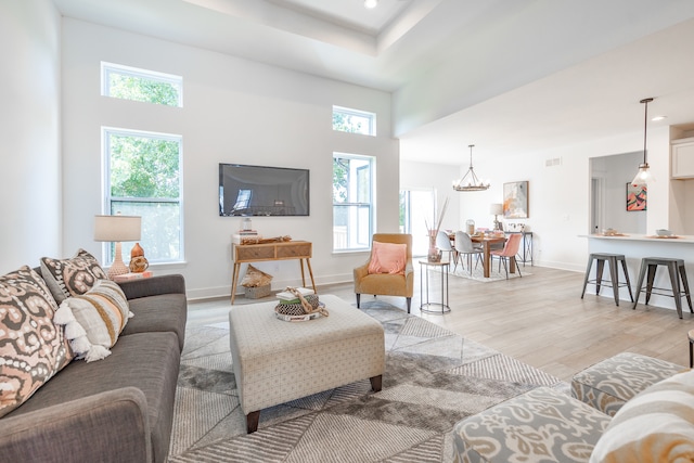 living room featuring a wealth of natural light, an inviting chandelier, and light hardwood / wood-style floors