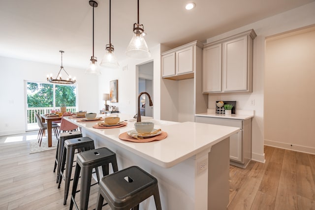 kitchen featuring light hardwood / wood-style floors, hanging light fixtures, a chandelier, and a center island with sink