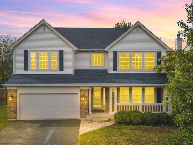 view of front of home featuring a garage, covered porch, and a yard