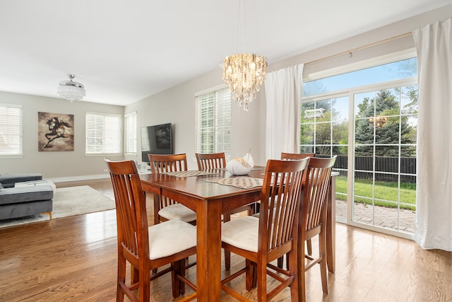 dining room with an inviting chandelier, plenty of natural light, and light hardwood / wood-style flooring