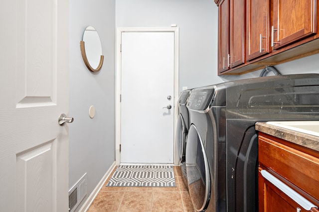 clothes washing area with cabinets, independent washer and dryer, and light tile patterned floors