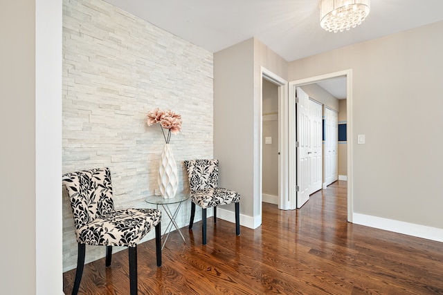 sitting room featuring dark wood-type flooring and an inviting chandelier