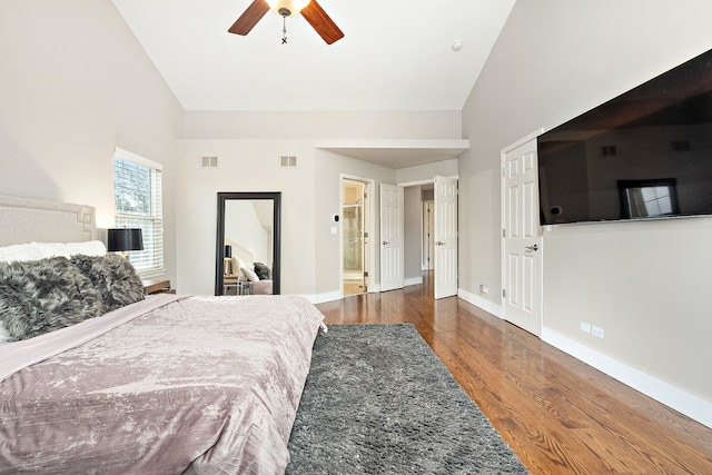 bedroom with dark wood-type flooring, high vaulted ceiling, connected bathroom, and ceiling fan