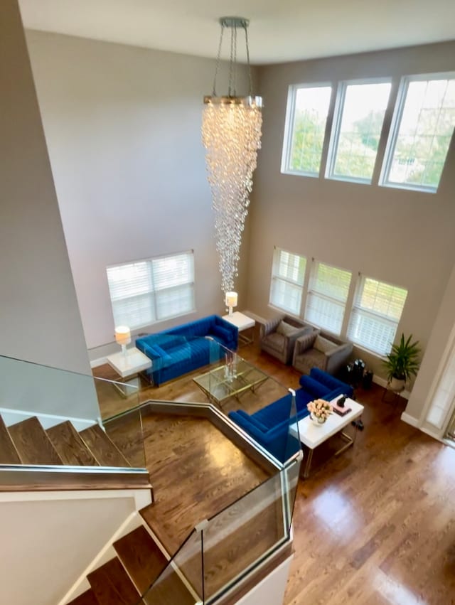 unfurnished living room featuring a towering ceiling, wood-type flooring, and a notable chandelier