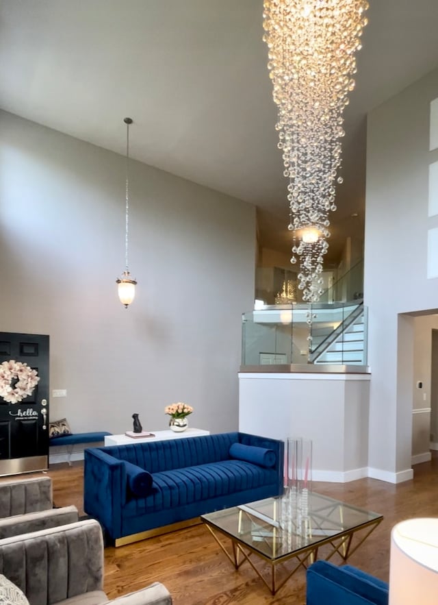 living room featuring a towering ceiling, wood-type flooring, and a notable chandelier