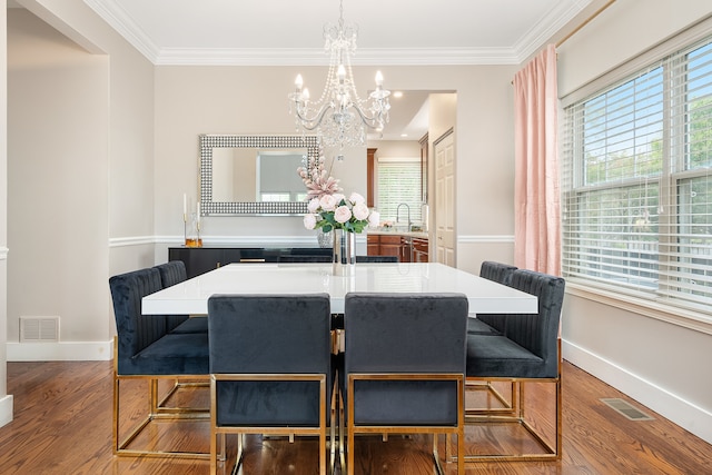 dining area with hardwood / wood-style floors, sink, crown molding, and a notable chandelier