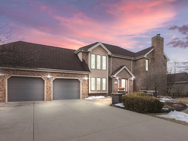 view of front of property with driveway, a chimney, roof with shingles, an attached garage, and brick siding