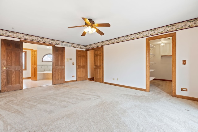 unfurnished bedroom featuring ensuite bath, a barn door, and light carpet