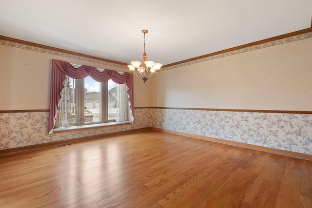 empty room with crown molding, hardwood / wood-style floors, and a notable chandelier