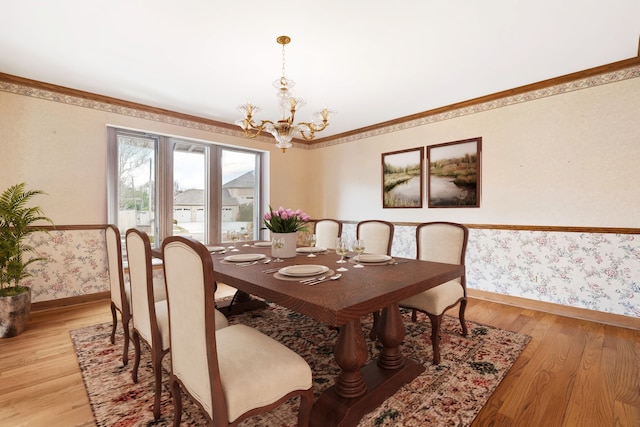 dining room featuring crown molding, a notable chandelier, light wood finished floors, baseboards, and wallpapered walls