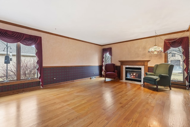 sitting room with ornamental molding, a fireplace with flush hearth, wood finished floors, and wainscoting