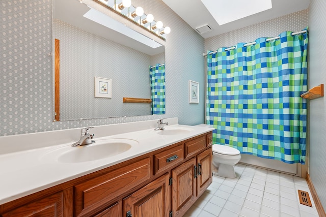 full bathroom with tile patterned flooring, a skylight, vanity, toilet, and shower / bath combo with shower curtain