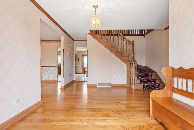 foyer featuring hardwood / wood-style floors, a notable chandelier, and ornamental molding