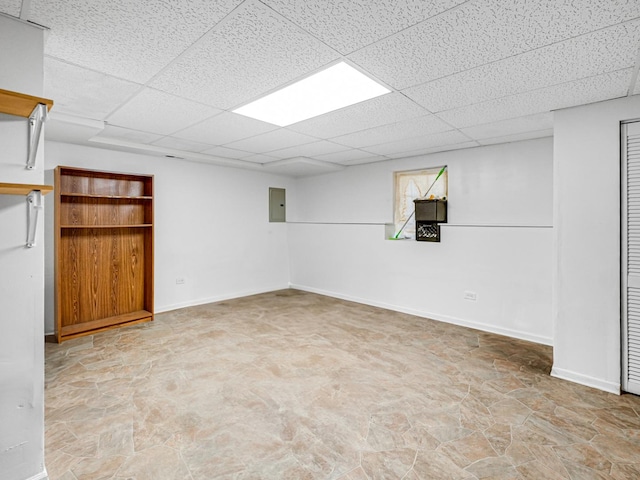 basement with a paneled ceiling and electric panel