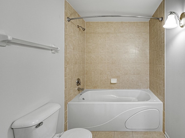 bathroom featuring tile patterned flooring, toilet, and tiled shower / bath