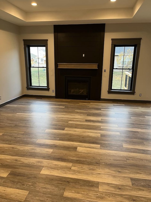 unfurnished living room featuring a fireplace, plenty of natural light, and wood-type flooring