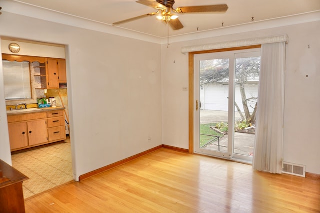 unfurnished room with ceiling fan, sink, light wood-type flooring, and crown molding