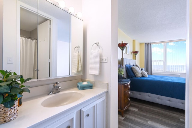 bathroom featuring connected bathroom, wood finished floors, a textured ceiling, and vanity