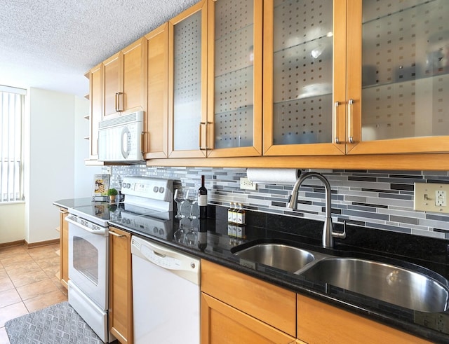 kitchen with light tile patterned floors, decorative backsplash, a sink, a textured ceiling, and white appliances