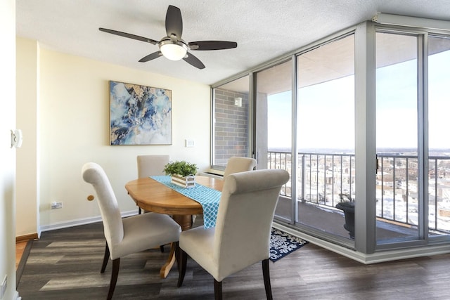 dining area featuring a textured ceiling, baseboards, a wall of windows, and wood finished floors