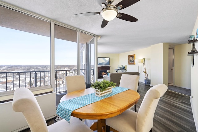 dining area featuring a textured ceiling, a lit fireplace, expansive windows, and wood finished floors