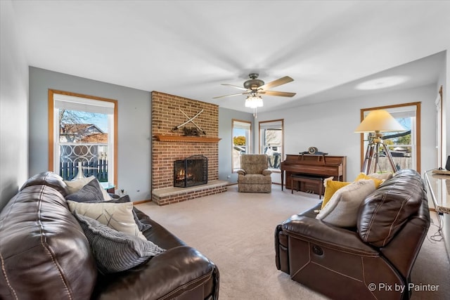 carpeted living room featuring a fireplace, ceiling fan, and plenty of natural light