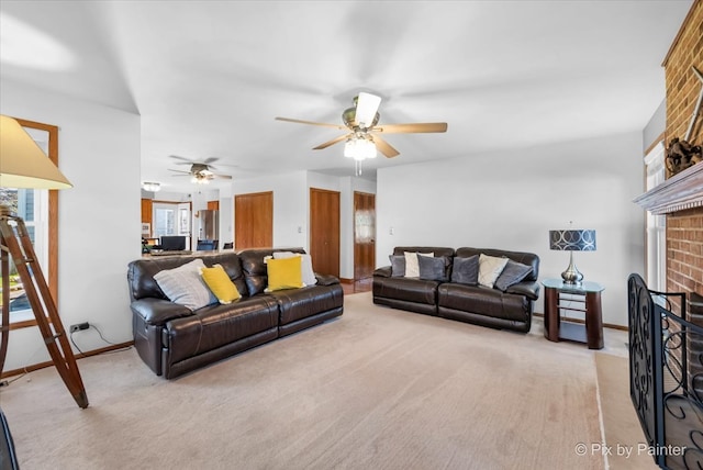 living room featuring a fireplace, light colored carpet, and ceiling fan