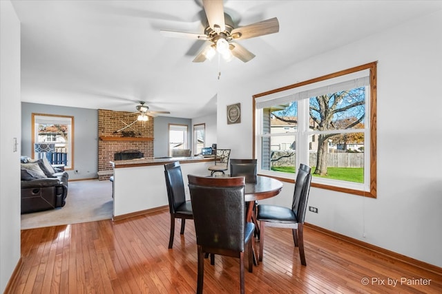 dining area with a brick fireplace, plenty of natural light, and ceiling fan