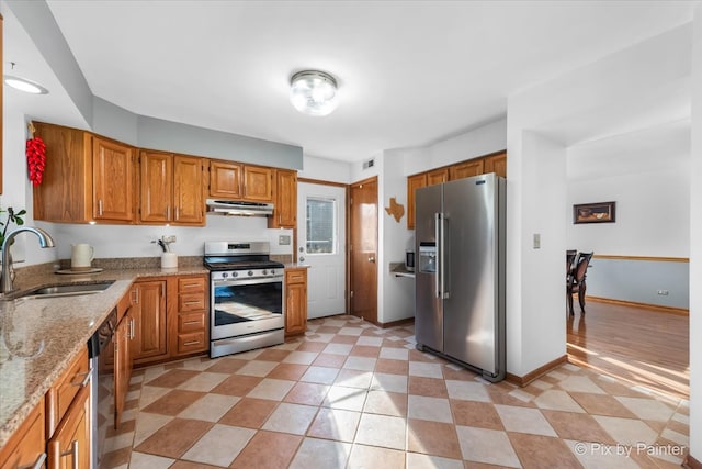 kitchen featuring stainless steel appliances, light stone counters, and sink