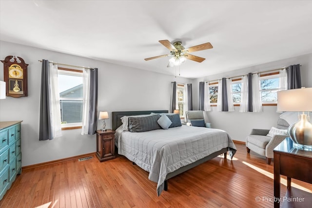 bedroom with ceiling fan, light wood-type flooring, and multiple windows