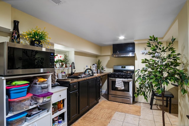 kitchen with wall chimney exhaust hood, light tile patterned floors, sink, and appliances with stainless steel finishes