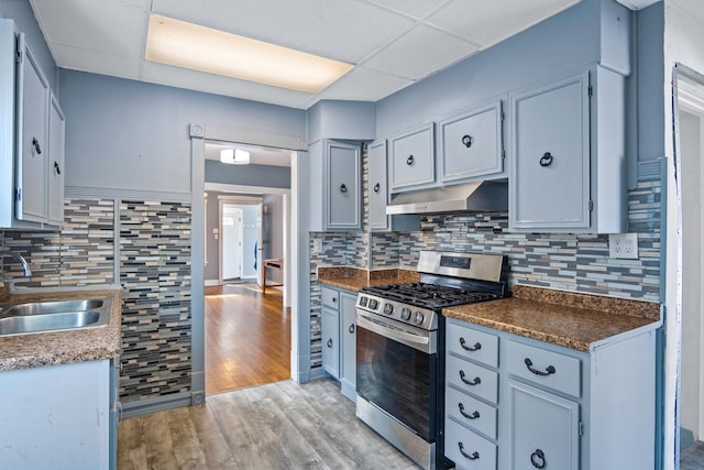 kitchen featuring light wood-type flooring, a paneled ceiling, backsplash, sink, and stainless steel range with gas cooktop