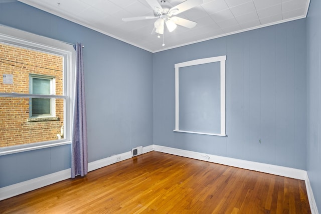 spare room with ceiling fan, wooden walls, wood-type flooring, and ornamental molding