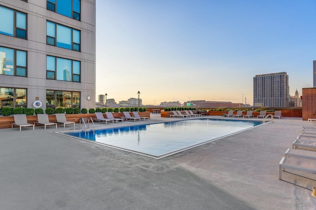 pool at dusk featuring a patio