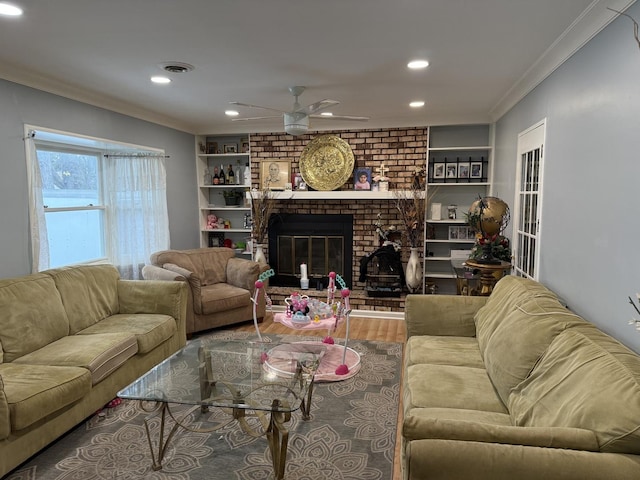 living room featuring built in shelves, ceiling fan, hardwood / wood-style floors, a fireplace, and ornamental molding