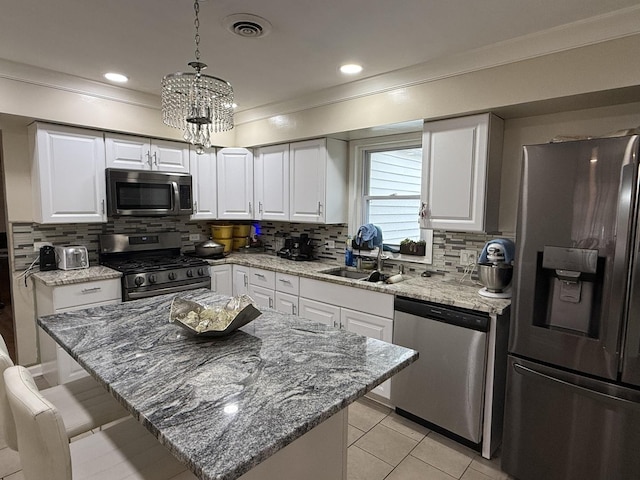 kitchen featuring sink, hanging light fixtures, stainless steel appliances, backsplash, and white cabinets