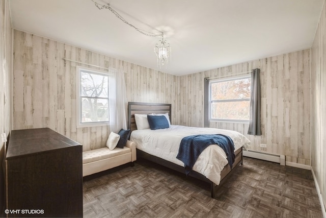 bedroom with multiple windows, dark parquet floors, a baseboard radiator, and an inviting chandelier