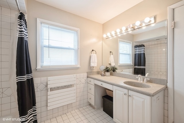 bathroom featuring tile patterned flooring, vanity, a wealth of natural light, and tile walls