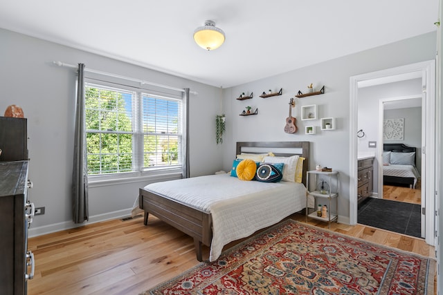 bedroom with ensuite bathroom and light wood-type flooring