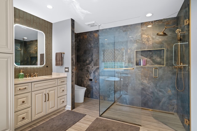 bathroom featuring tile walls, wood-type flooring, a shower with door, vanity, and toilet