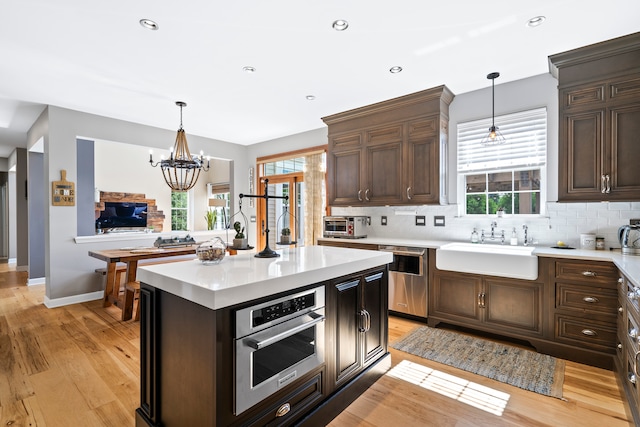 kitchen with a wealth of natural light, appliances with stainless steel finishes, a notable chandelier, and light hardwood / wood-style flooring